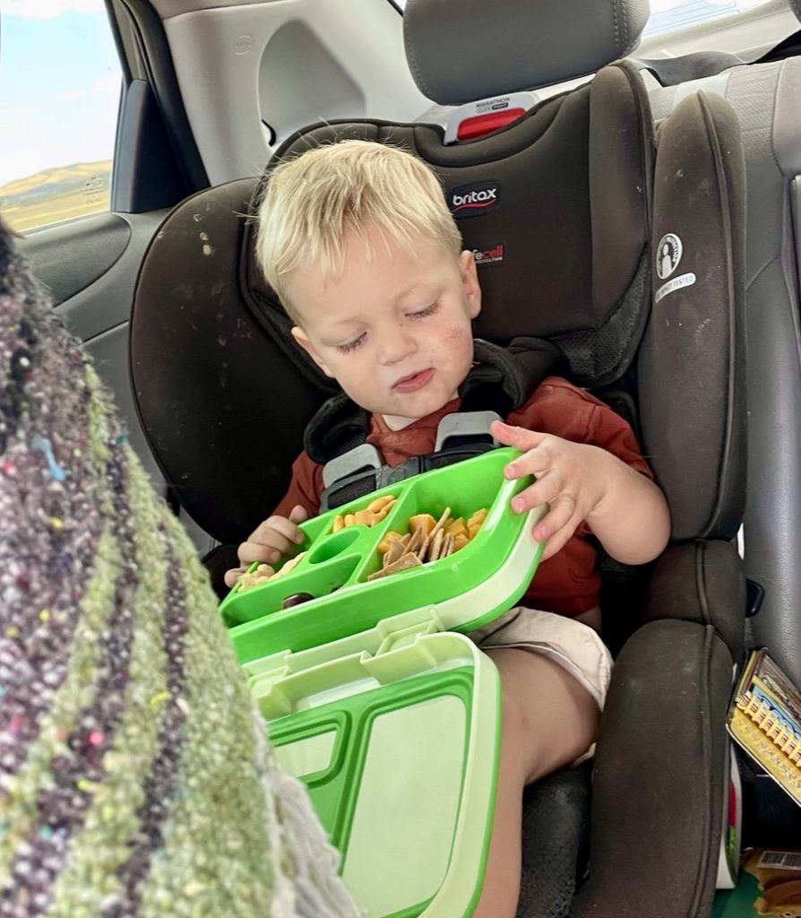 toddler eating favorite snacks on a road trip