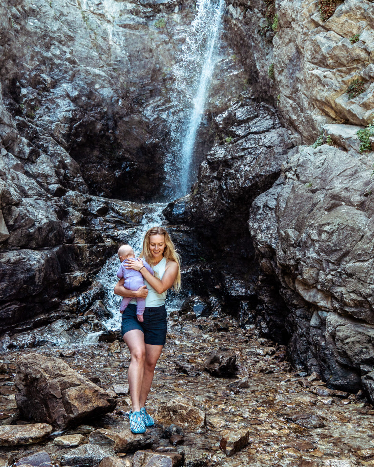 Mom hiking with baby near a waterfall