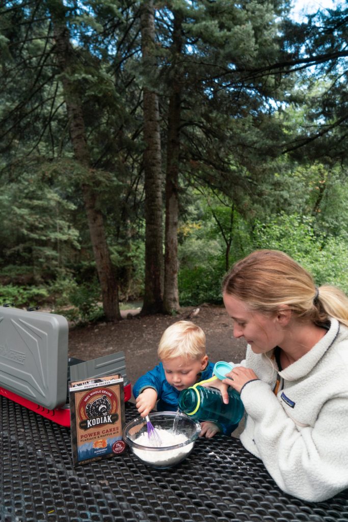 Mom and toddler making pancake mix while backpacking