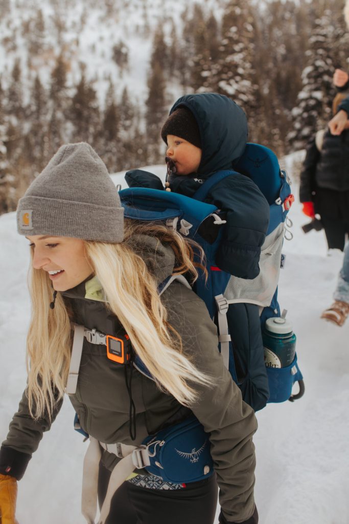 Mom winter hiking with baby in framed child carrier